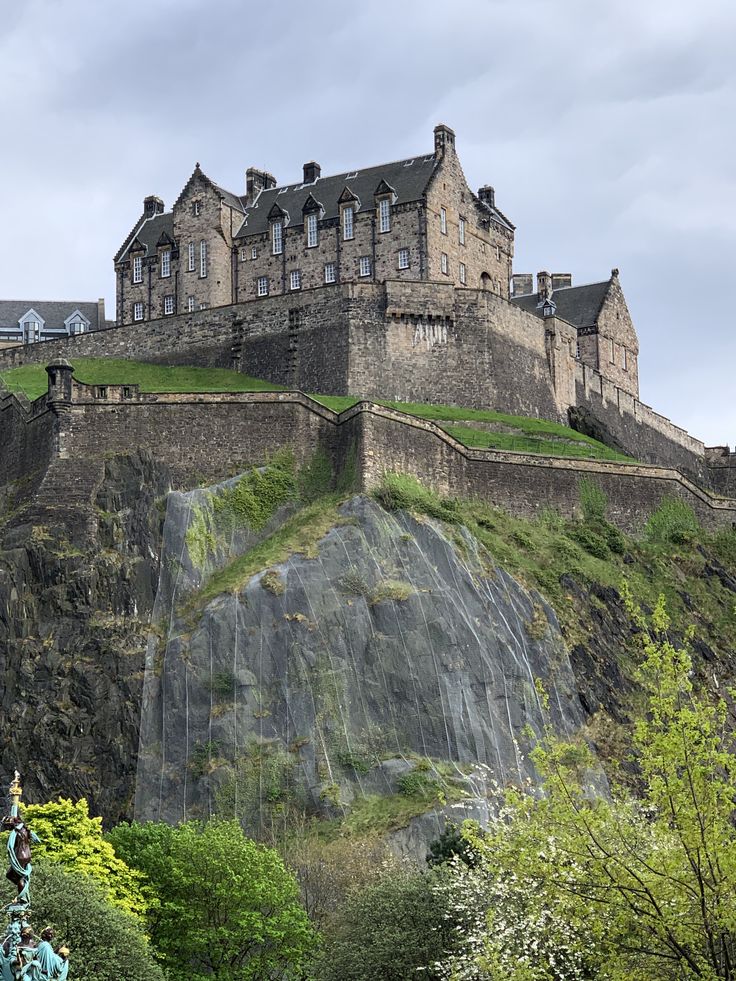 Edinburgh Castle on rocky cliff with stone walls and towers against cloudy sky
