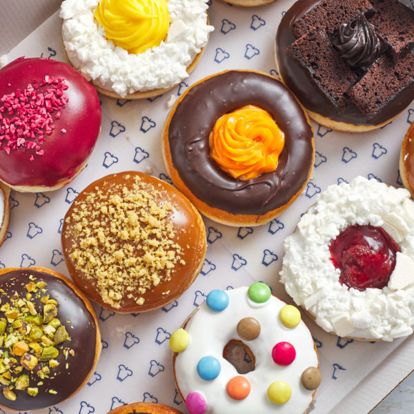 Top view of assorted donuts with colorful toppings and decorations arranged on white surface