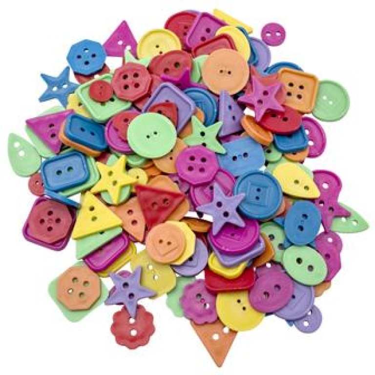Assorted colorful plastic craft buttons in various shapes scattered on a white background
