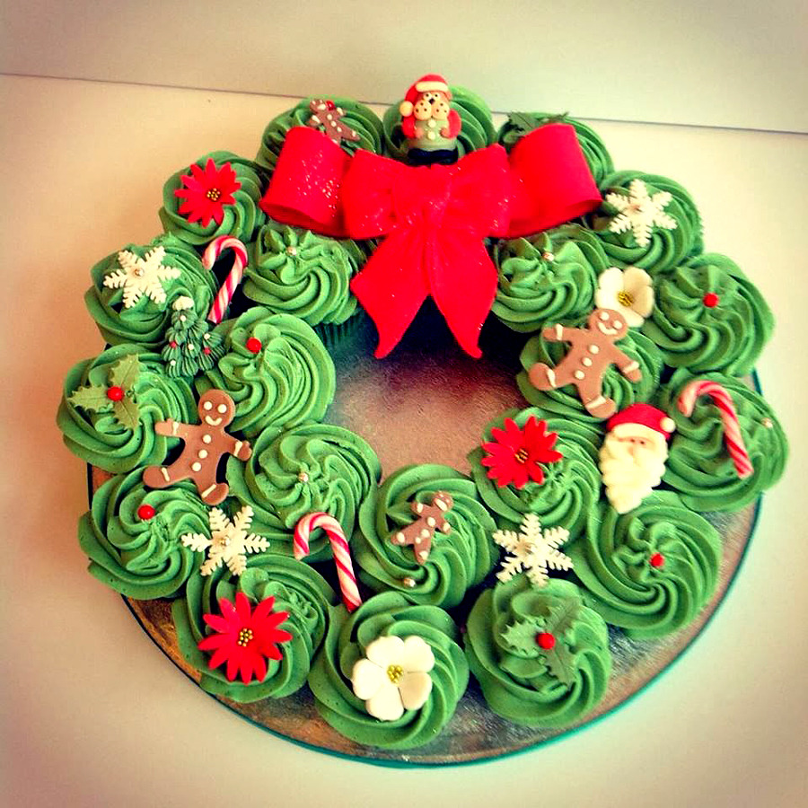 Christmas wreath made of decorated green cupcakes with a large red bow on top