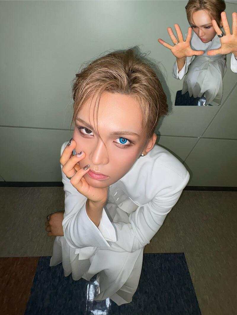 Young man with blonde hair and blue eyes in white shirt posing with mirror reflection behind him