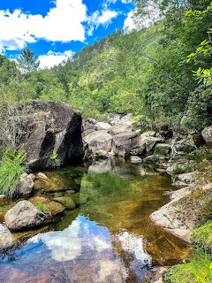 Rocky stream with clear water surrounded by boulders and green trees in Gerês National Park, Portugal