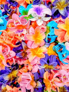 Colorful tropical flower hair clips piled together in bright pink, purple, orange, blue, and yellow