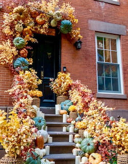 Brooklyn brownstone entrance decorated with pumpkins, gourds, and autumn leaves on steps and around the door