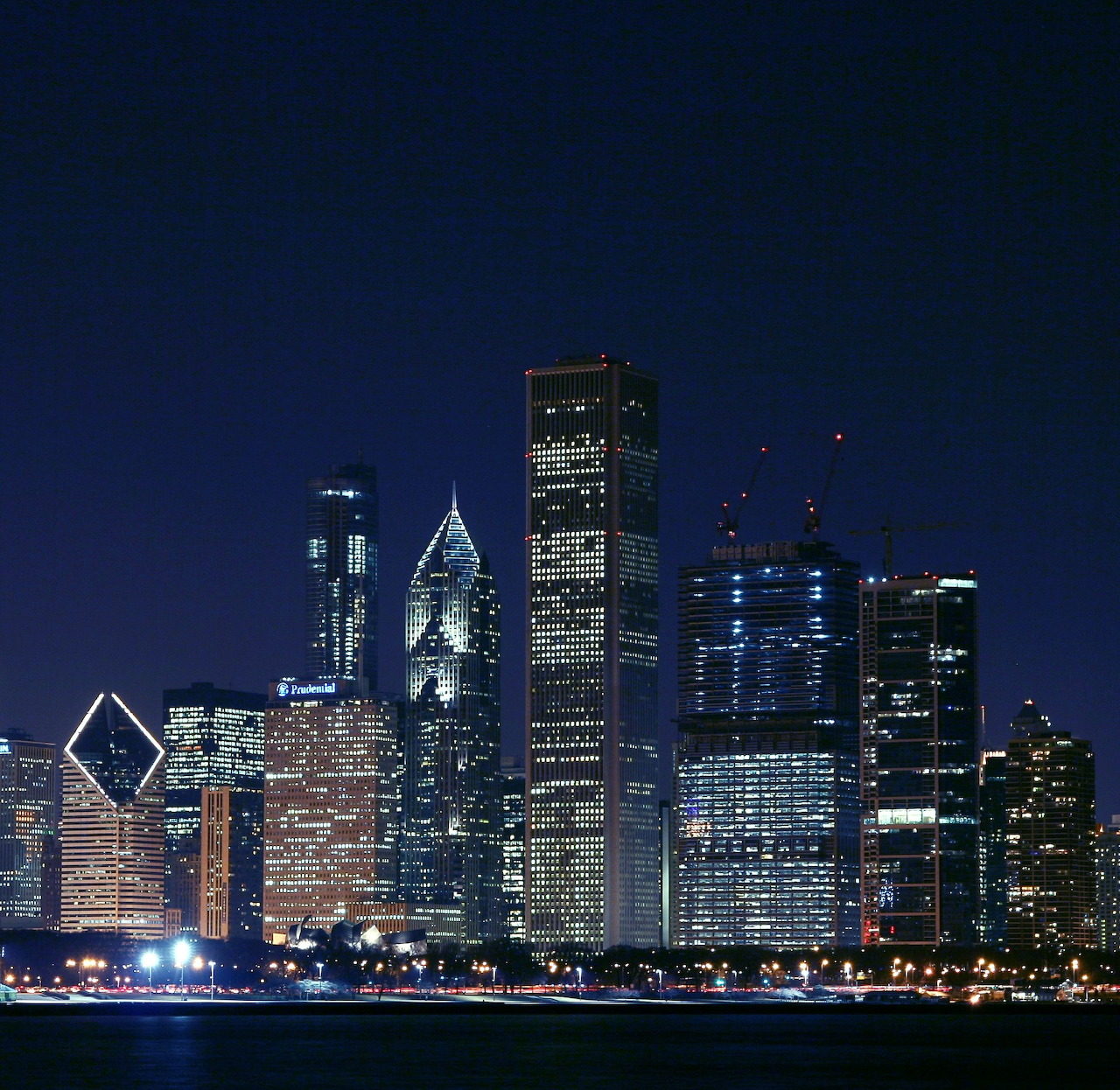 City skyline with lit skyscrapers at night beside dark water