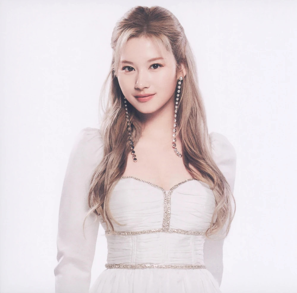 Studio portrait of TWICE member Sana wearing a white dress and long earrings