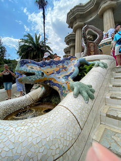 Colorful mosaic salamander sculpture at Parc Güell staircase in Barcelona with tourists nearby