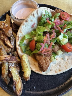 Chicken taco with salad toppings, fries, and a small cup of dipping sauce on a plate