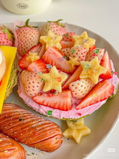 Pink bowl of strawberries and star fruit with croissant on plate