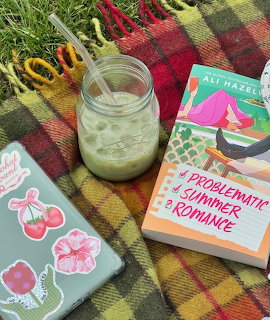 Iced matcha drink in mason jar next to books and stickers on plaid blanket