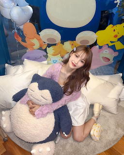 Woman in purple top sitting with oversized plush penguin toy among decorative pillows in studio