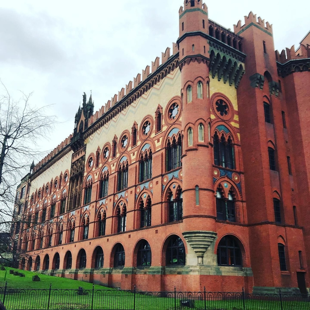 Red brick Victorian Gothic factory building with ornate arched windows and corner turret in Glasgow