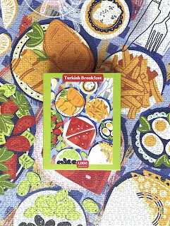 Illustrated Turkish breakfast spread with bread, eggs, watermelon, olives, and various dishes on blue tablecloth