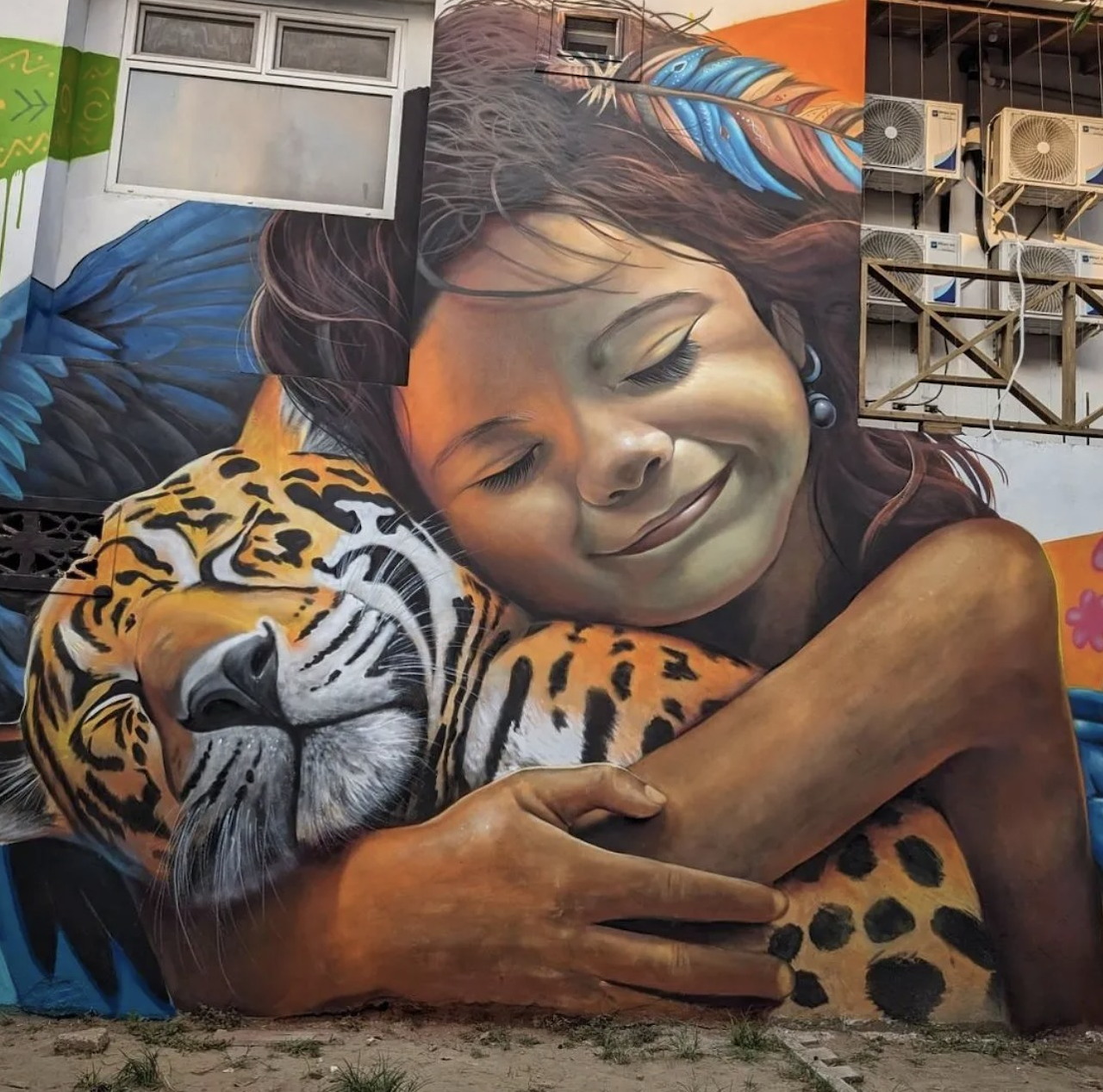 Graffiti mural of a girl hugging a jaguar painted on a building wall