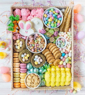 Pastel Easter charcuterie board with bunny dip, candy eggs, cookies, macarons, and marshmallows