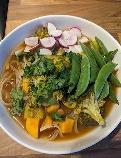 Bowl of vegetable noodle soup with broccoli, snap peas, radish, sweet potato, cilantro, and rice noodles