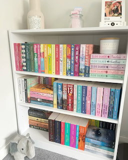 White bookshelf packed with colorful books and small decorative objects indoors.