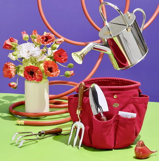 Garden tools with watering can and colorful flower bouquet on green surface with purple background