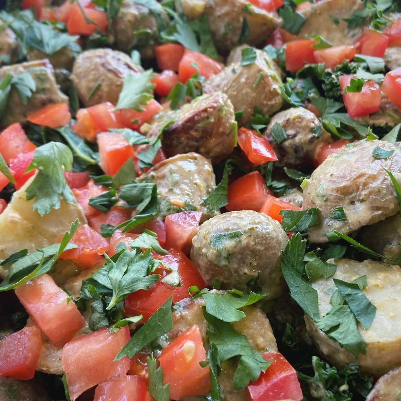 Close-up of salad with artichoke hearts, tomatoes, greens, and chopped herbs