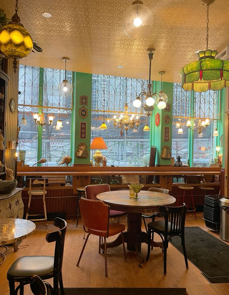 Vintage cafe interior with round tables, orange chairs, and hanging lamps by windows