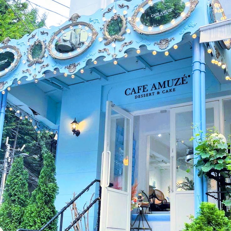 Blue cafe storefront with decorative white trim and plants