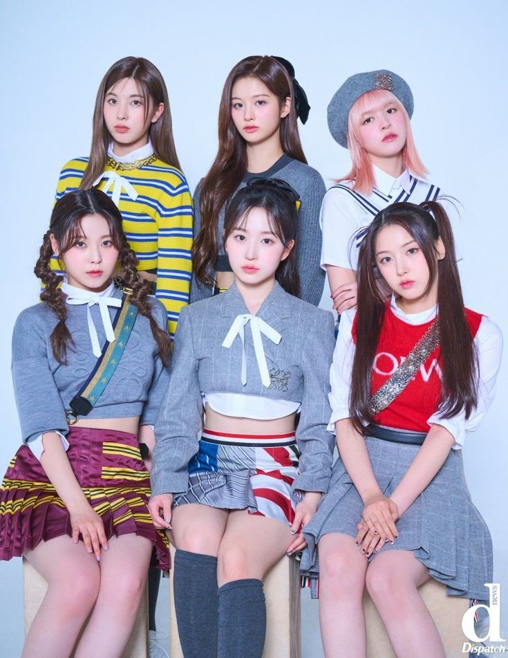 Six young women in stylish colorful outfits posing together in a studio group photo