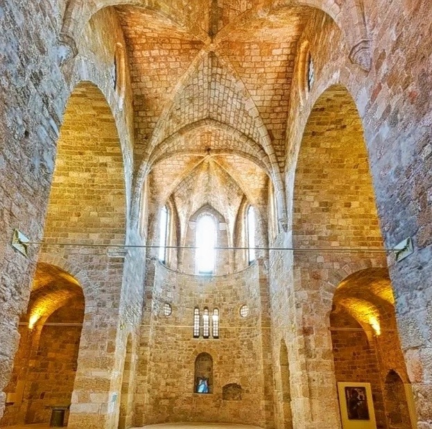 Stone church interior with arched ceiling, brick vaults, and glowing alcoves