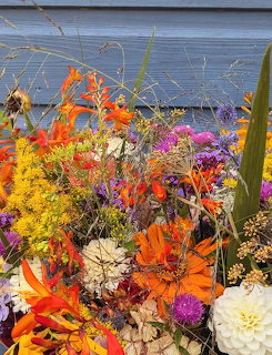 Dried flower bouquet with orange, yellow, pink blooms against blue wooden wall