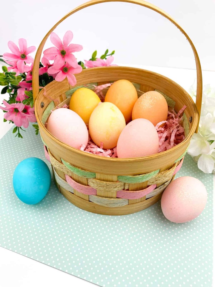 Woven basket with pastel colored Easter eggs and pink flowers