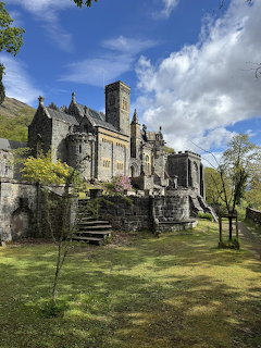 St Conan's Kirk stone church with tower, stone stairs, green lawn, and cloudy sky in Scotland