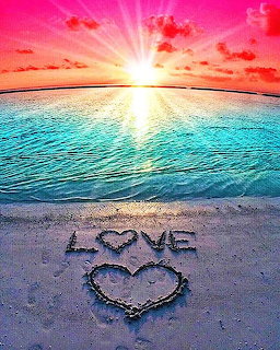Sunrise over a beach with turquoise water and LOVE written in the sand with a heart shape