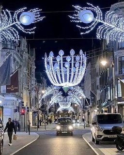London street at night with elaborate white holiday light decorations forming arches overhead