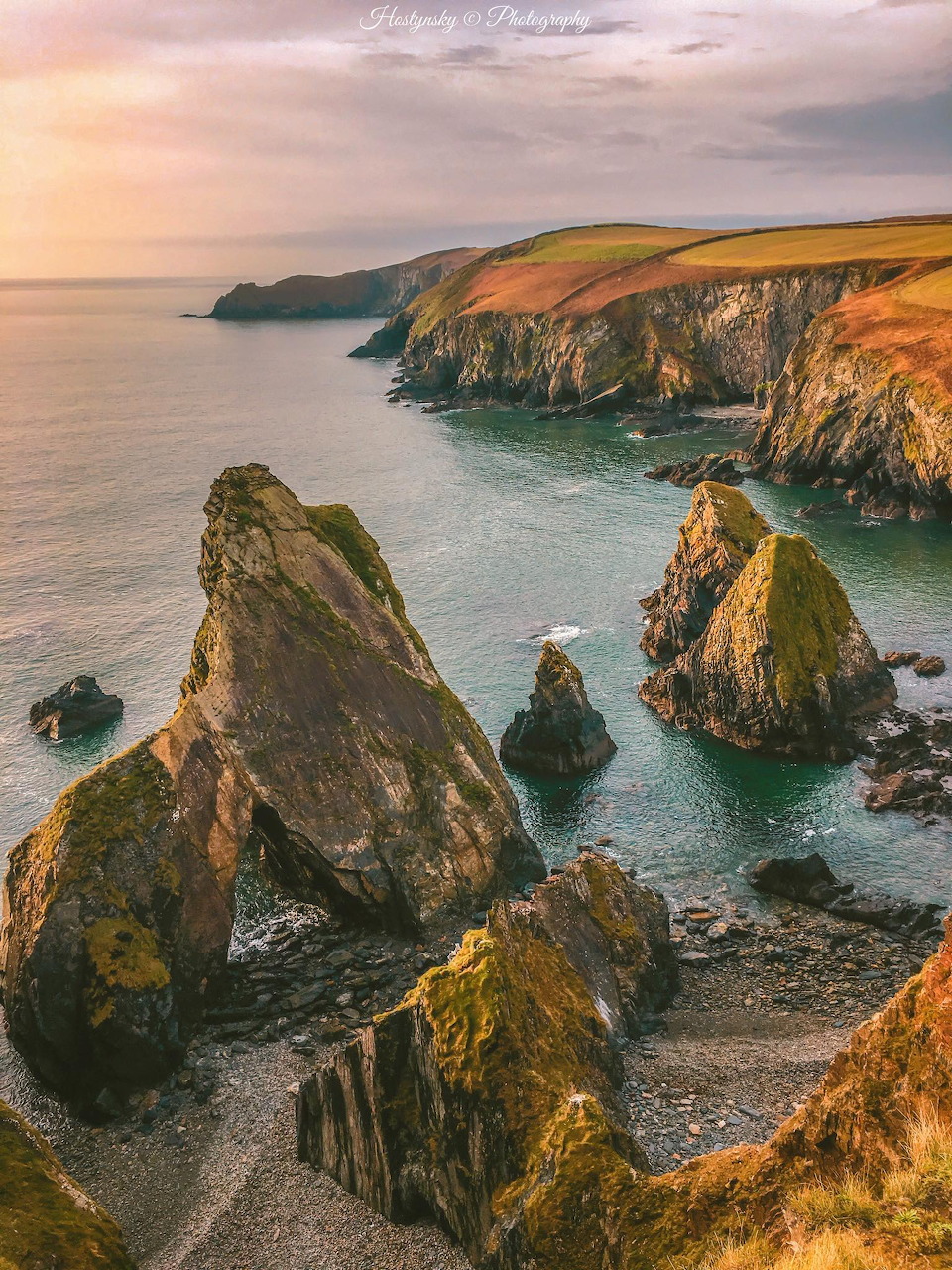 Dramatic sea stacks and rocky cliffs at Nohoval Cove, Cork, Ireland at golden sunset