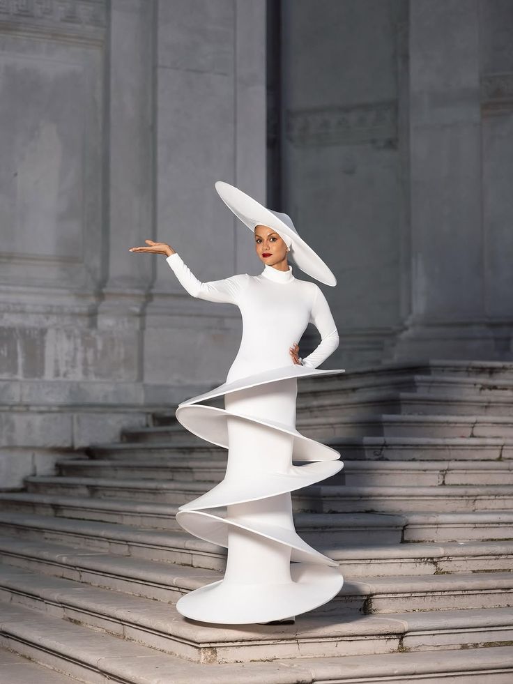 Model in futuristic white sci-fi dress and wide-brim hat