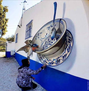 Woman kneeling by a surreal wall mural of a giant bowl and spoon with a hummingbird