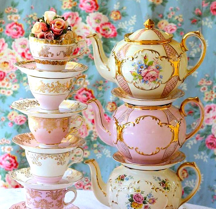 Stack of ornate vintage teacups and teapots with floral designs and gold accents