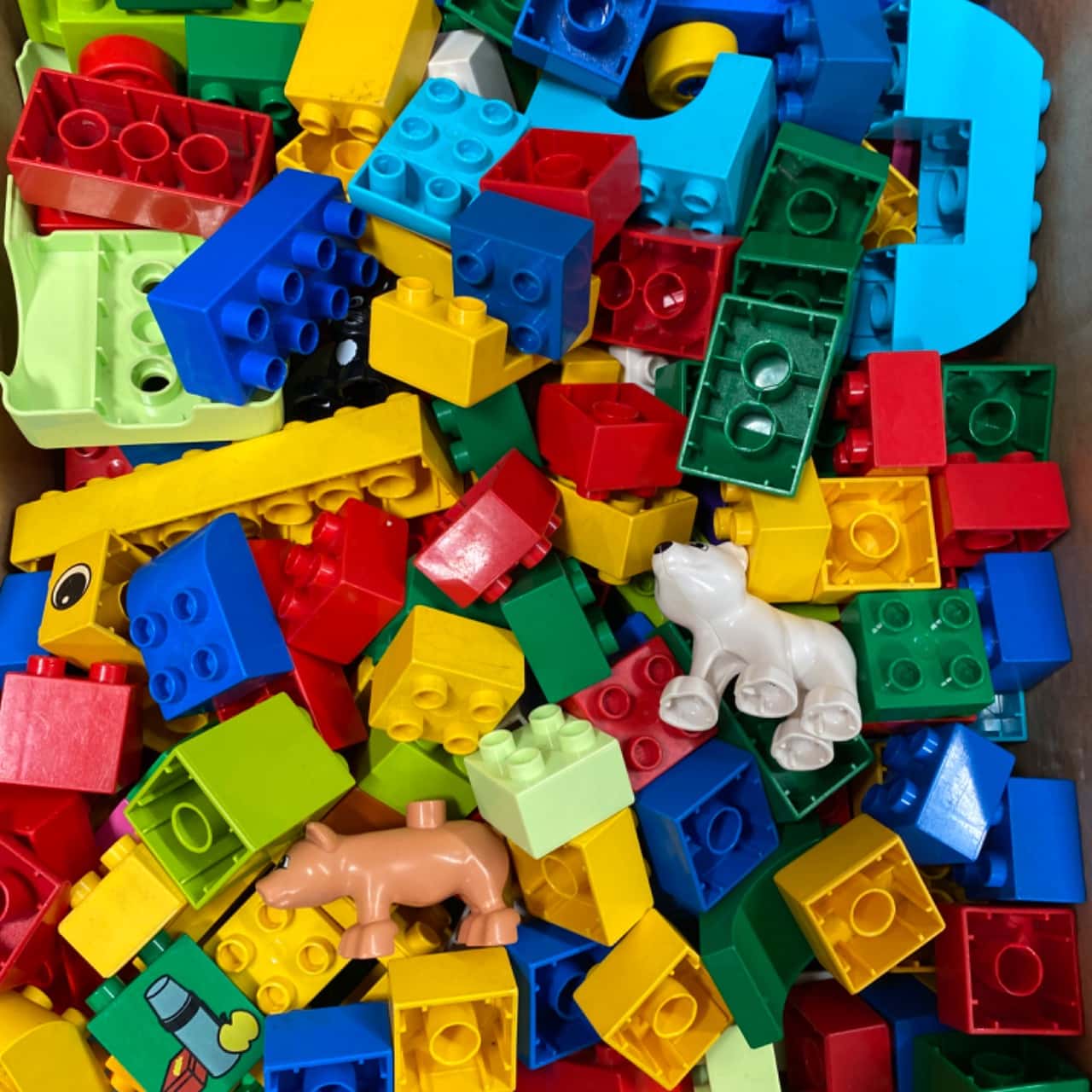 Pile of colorful Duplo-style toy blocks with small animal pieces