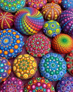 Colorful stones hand-painted with intricate mandala dot patterns in rainbow colors