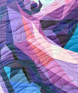 Abstract quilt with flowing geometric shapes in purple, pink, and teal with decorative stitching
