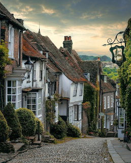 Cobblestone street with white cottages, ivy-covered walls, and vintage lamp in an English village