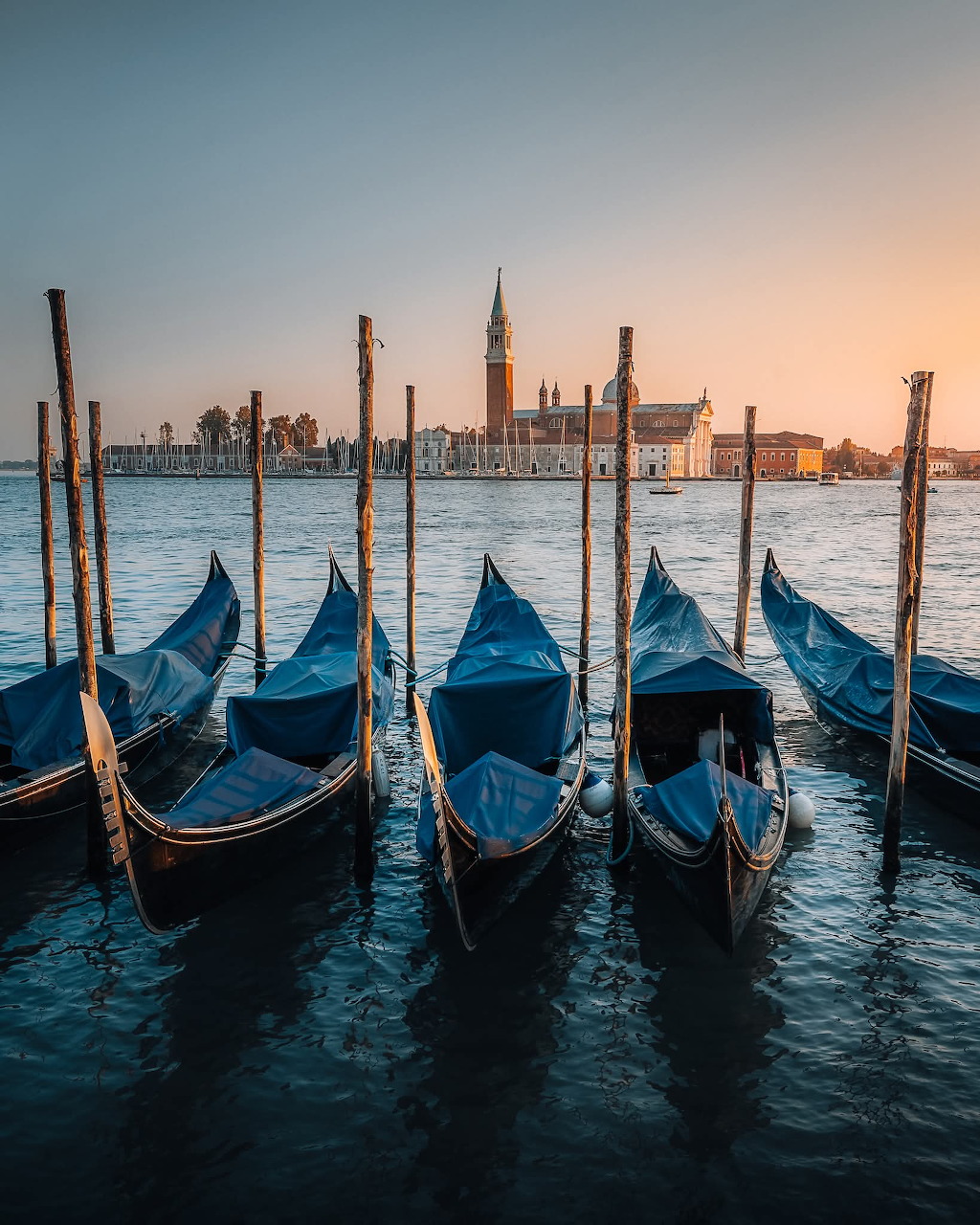 Gondolas moored in Venice lagoon at sunset with San Giorgio Maggiore church in the background
