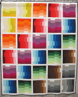 Quilt with grid of colorful gradient squares arranged in rainbow spectrum