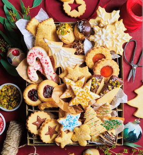 Assorted homemade Christmas cookies and pastries on a red holiday table, viewed from above