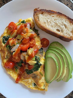 Colorful vegetable omelette with avocado slices and toasted bread on white plate
