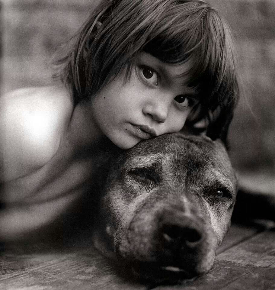Black-and-white close-up of a child resting beside a large dog