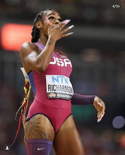 Female track athlete in a red USA racing uniform at a stadium