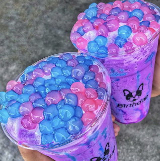 Two purple galaxy boba drinks with blue and pink heart-shaped jelly toppings in plastic cups