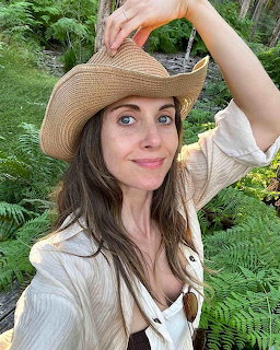 Woman in a straw hat posing outdoors among green ferns