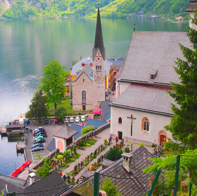 Aerial view of Hallstatt village church and buildings beside mountain lake with forested slopes