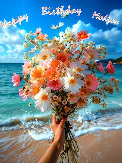 Hand holding large colorful flower bouquet on beach with ocean and blue sky background